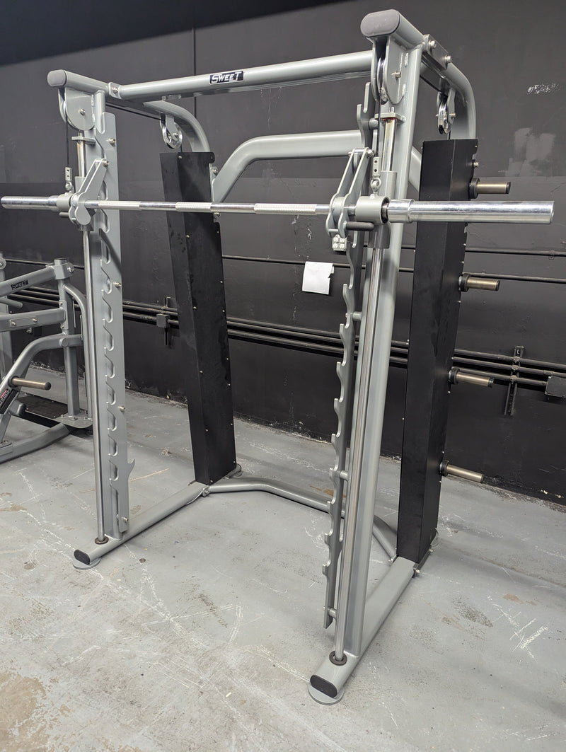 Muscle D Fitness Sweet Smith Machine FW-SW-SM with barbell and weight plates in a gym setting.