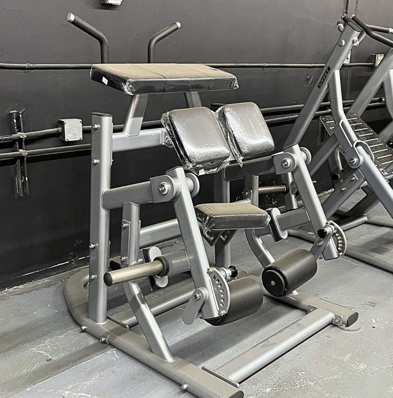 Muscle D Fitness Pro Strength adjustable kneeling leg curl machine in silver, plate loaded for targeting hamstring muscles.