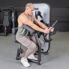 Muscle D Fitness Vogue Biceps Triceps Combo selectorized machine with padded arm supports and weight stacks for strength training.