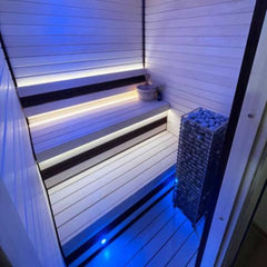 SAKSBY WHOLESALE Huum Cliff Slim electric stainless steel sauna heater with two prop blocks inside a sauna room.