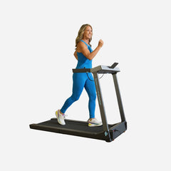 WalkingPad Denise Austin foldable treadmill for home use, woman walking on the treadmill in a modern gym setting