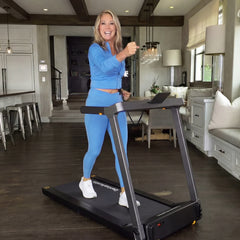 WalkingPad Denise Austin 2.0 foldable treadmill in blue, showing the user walking on the compact treadmill in a home setting.