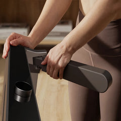 Woman adjusting handrail on WalkingPad Denise Austin foldable treadmill for home exercise.