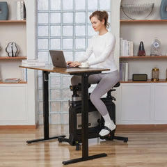 WalkingPad foldable exercise bike for under-desk workouts, shown standing next to a desk in a home office setting.